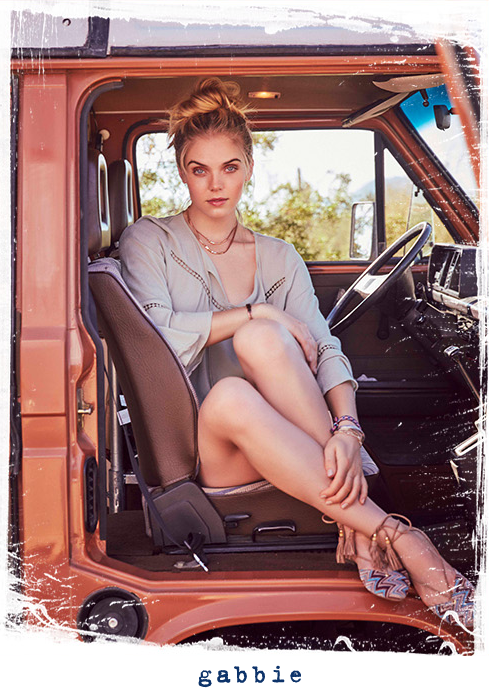 Girl sitting in front seat of truck facing outward wearing Gabbie.