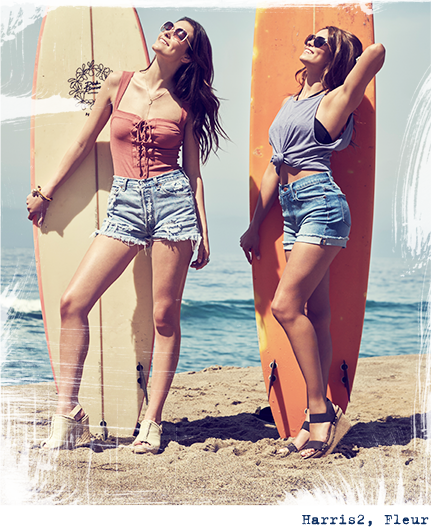 Two girls standing up against surfboards on the beach.